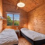 Zwei Betten in einem Holzraum mit Fenster und Nachttisch.