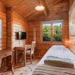Ein Schlafzimmer mit Holzwand, Bett, Schreibtisch und Fernseher.