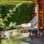 Terrasse mit Liegestühlen und Holzwand. Hintergrund: grüner Heckenbereich.