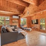 Holzvertäfelte Wohnräume mit Sofa, Fernseher und Fenstern.