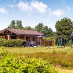 Holzhäuschen mit Garten, Spielplatz und Sitzgelegenheiten.