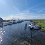 Schiff im Hafen mit grünen Ufern und blauem Himmel.