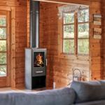 Holzhaus mit Kamin, Fenster und Tür. Sofa im Vordergrund.