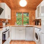 Küche mit Holzwand, Fenster, Spüle, Waschmaschine und Trockner.