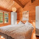 Schlafzimmer mit Holzwänden, Bett, Fenster und weißen Schränken.