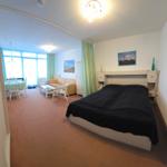 Schlafzimmer mit Bett und Wohnbereich mit Sofa und Tisch.