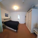 Schlafzimmer mit Bett, Kleiderschrank und Stuhl.