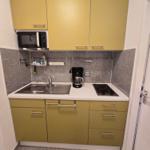 Küche mit gelben Schränken, Herd, Spüle und Mikrowelle.