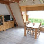 Essbereich mit Holztisch und Stühlen. Fenster mit Blick auf grüne Landschaft.