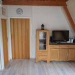 Zimmer mit Holzboden, TV-Möbel und Holztüren unter Dachschräge.