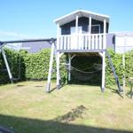 Haus mit Spielplatz, Schaukel und Hängematte im Garten.