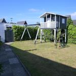 Hinterhof mit Spielhaus, Schaukel und grünem Rasenbereich.