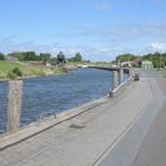 Wasserweg mit Steg, Uferweg und Blick auf Schleusenturm und Grünflächen.