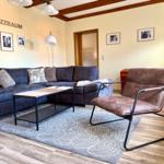 Heller Wohnbereich mit Ecksofa, Ledersessel und Holzbalken - gemütliches Wohnzimmer der Ferienwohnung Harztraum in Blankenburg Harz