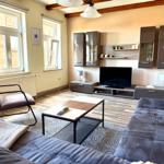 Heller Wohnbereich mit Ecksofa, Ledersessel und Holzbalken - gemütliches Wohnzimmer der Ferienwohnung Harztraum in Blankenburg Harz