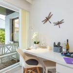 Schreibtisch mit Stuhl und Blick auf Balkon mit Garten.