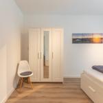 Schlafzimmer mit Bett, Kleiderschrank und Wandbild.