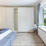 Schlafzimmer mit Bett, Kleiderschrank und Fenster mit Pflanzen.
