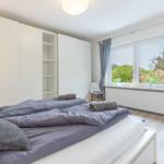 Schlafzimmer mit Doppelbett, Kleiderschrank und Fenster mit Blick auf Garten.