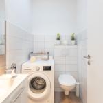 Badezimmer mit Waschmaschine, Toilette und Spiegel