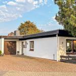Moderne weiße Villa mit Garage und Terrasse im Grünen.