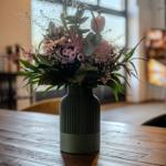 Blumenstrauß in grünem Vase auf Holztisch