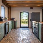 Küche mit Steinboden, Holzbalken und Blick auf Garten