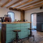 Küche mit Holzbalken, grünen Schränken und schwarzer Kühlschrank