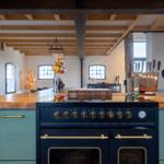 Küche mit Holzdecke, blauen Schränken und Edelstahlherd.