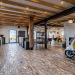 Küche und Essbereich mit Holzbalken und Kachelboden. Ein Scooter steht im Raum.