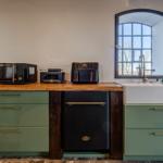 Küche mit grünen Schränken, Holzoberfläche und moderner Spüle.