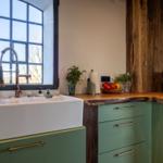 Küche mit grünen Schränken, Holzoberfläche und großem Fenster.