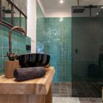 Badezimmer mit grünen Fliesen, Holzwaschtisch und Dusche