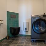 WC mit Waschmaschine und grünen Fliesen