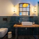 Bad mit Waschtisch auf Holz, Toilette und Spiegel mit Fensterform.