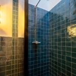 Duschkabine mit dunkelblauen Fliesen und Duschkopf an der Decke.