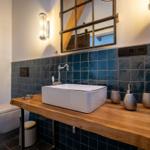 Badezimmer mit Holzwaschtisch, blauen Fliesen und Spiegel