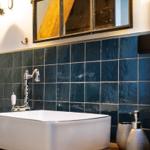 Waschbecken mit blauen Fliesen und Spiegel über dem Waschbecken.