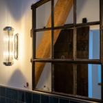 Wandlampe neben Spiegel mit Holzbalkenreflexion