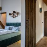 Schlafzimmer mit Bett, Wanddekoration und Holzdeckenbalken. Flur mit Holztür und Boden.