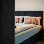 Schlafzimmer mit Bett, Kissen und Nachttisch mit Lampe.