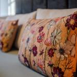 Sofa mit floralen Kissen in warmen Farbtönen.