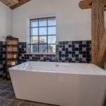 Bad mit freistehender Badewanne, Holzbalken und Fenster mit Blick.