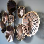 Metallkunstwerk an der Wand mit blätterförmigen Elementen.