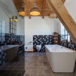 Badezimmer mit freistehender Badewanne, Holzbalken und schwarz-weißen Fliesen.