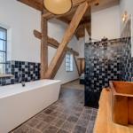 Badezimmer mit freistehender Badewanne, Dusche und Holzkonstruktion.