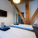 Schlafzimmer mit Holzbalken, Bett, Fernseher und Handtüchern.