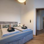 Schlafzimmer mit Doppelbett, Holzboden und Tür zum Flur.