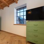 Zimmer mit grünem Schrank, Holzboden und TV auf Schrank.