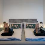 Doppelbett mit Kissen, Handtüchern und Bio-Kaffeebeuteln auf Nachttischen.